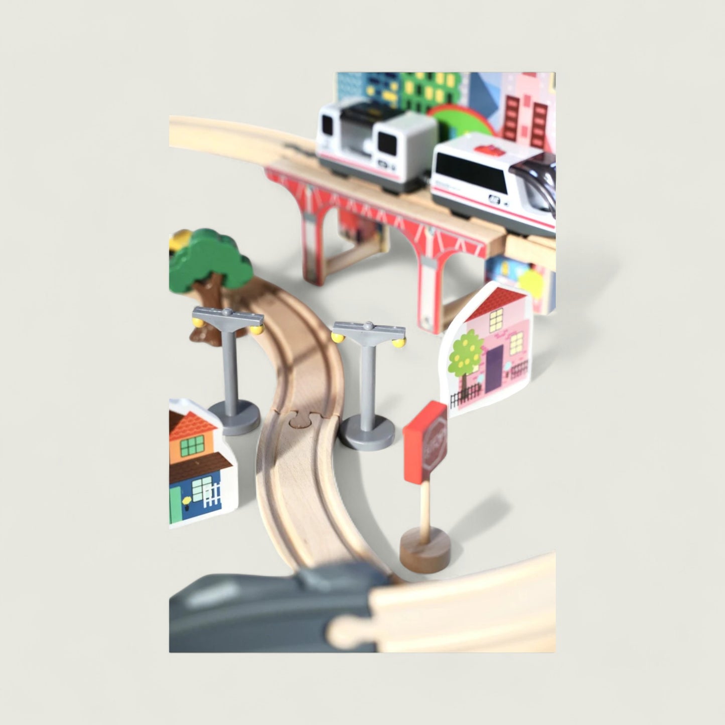 Toy train set with tracks and buildings on a light gray background