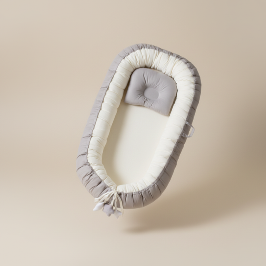 Gray and white baby nest with cushion on a beige background