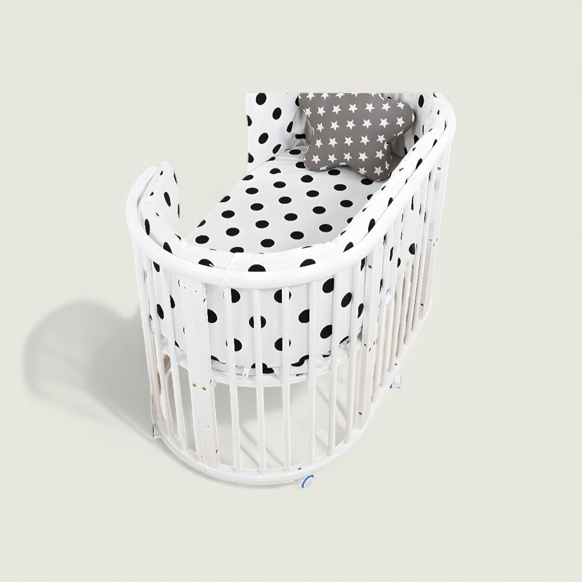 White crib with black polka dot bedding on a light gray background