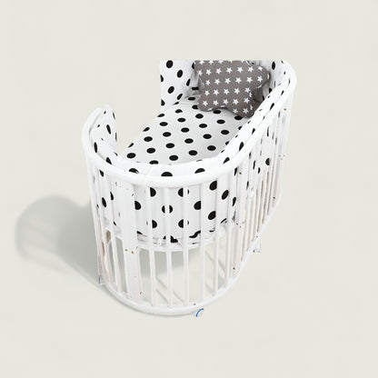 White crib with black polka dot bedding on a light gray background