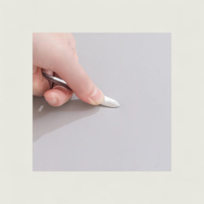 Hand holding a small metallic object on a light gray background