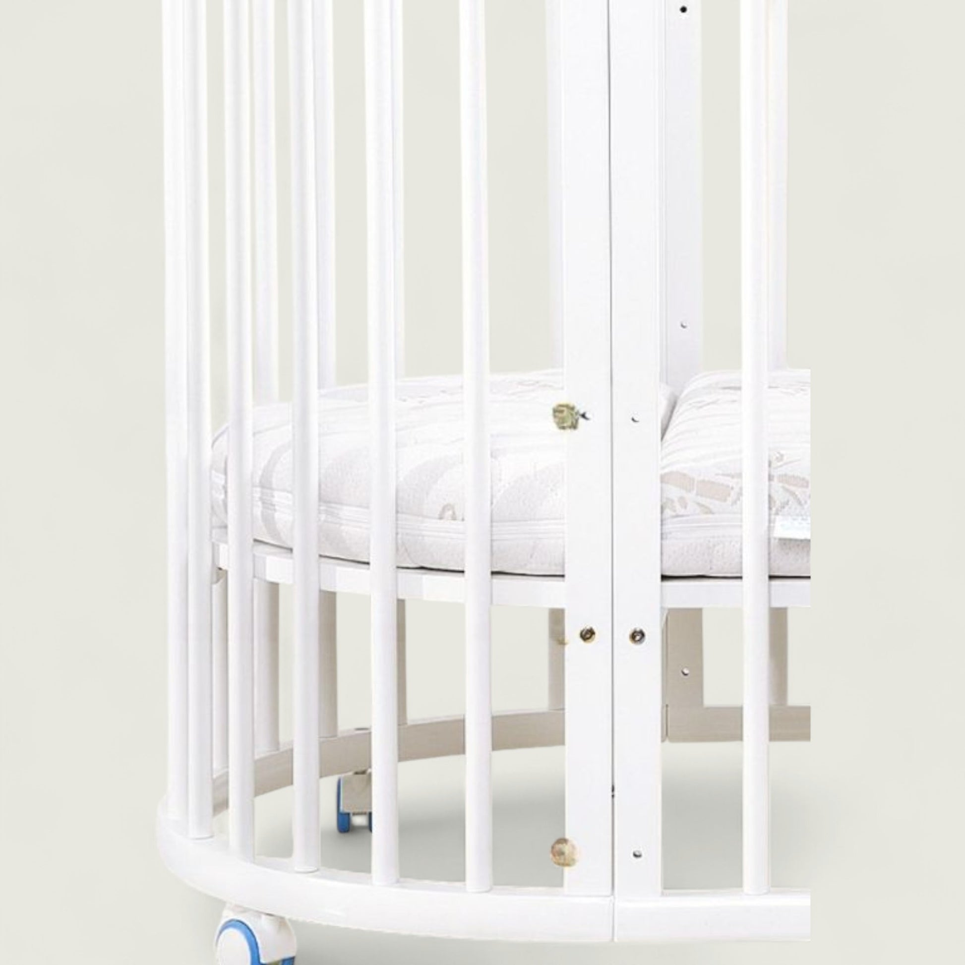 White crib with a white mattress in a minimalistic room.