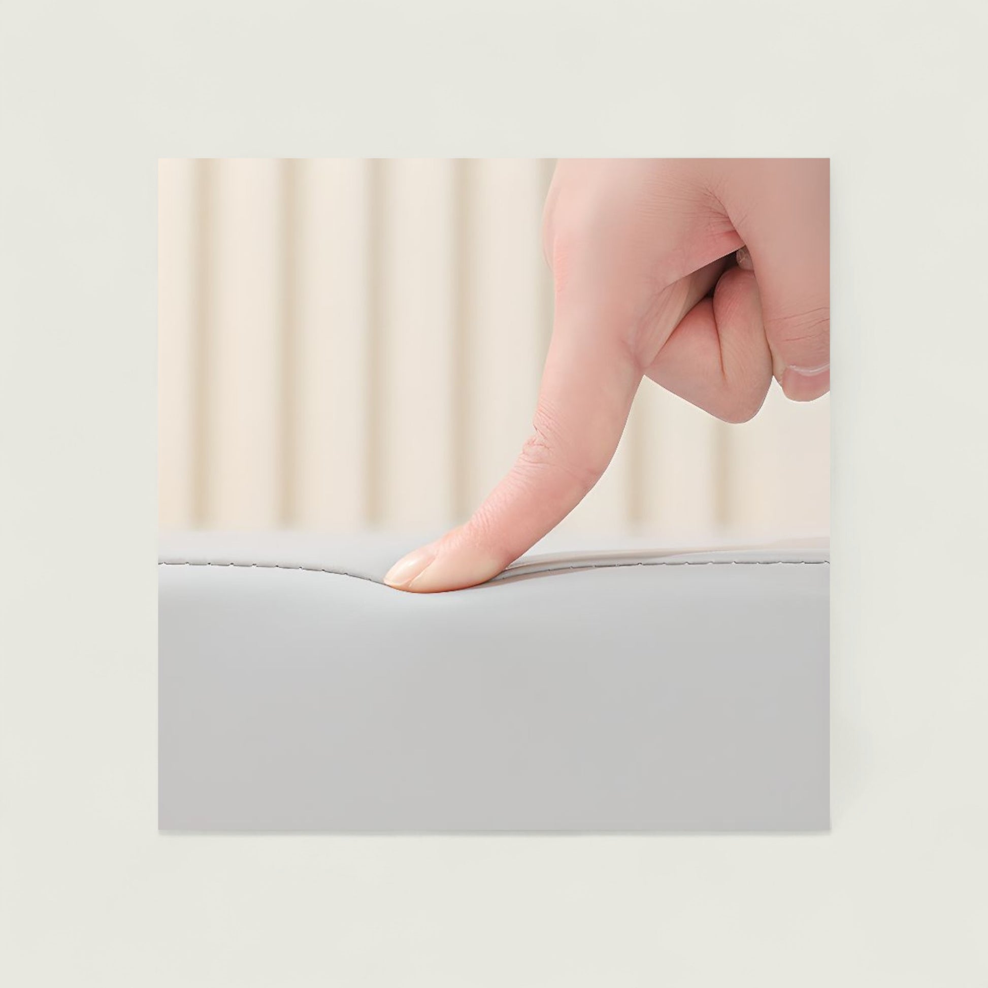 Hand pressing on a gray mattress topper with a blurred background
