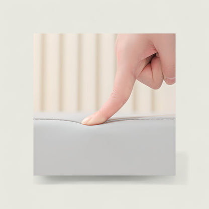 Hand pressing down on a gray mattress topper with a blurred background