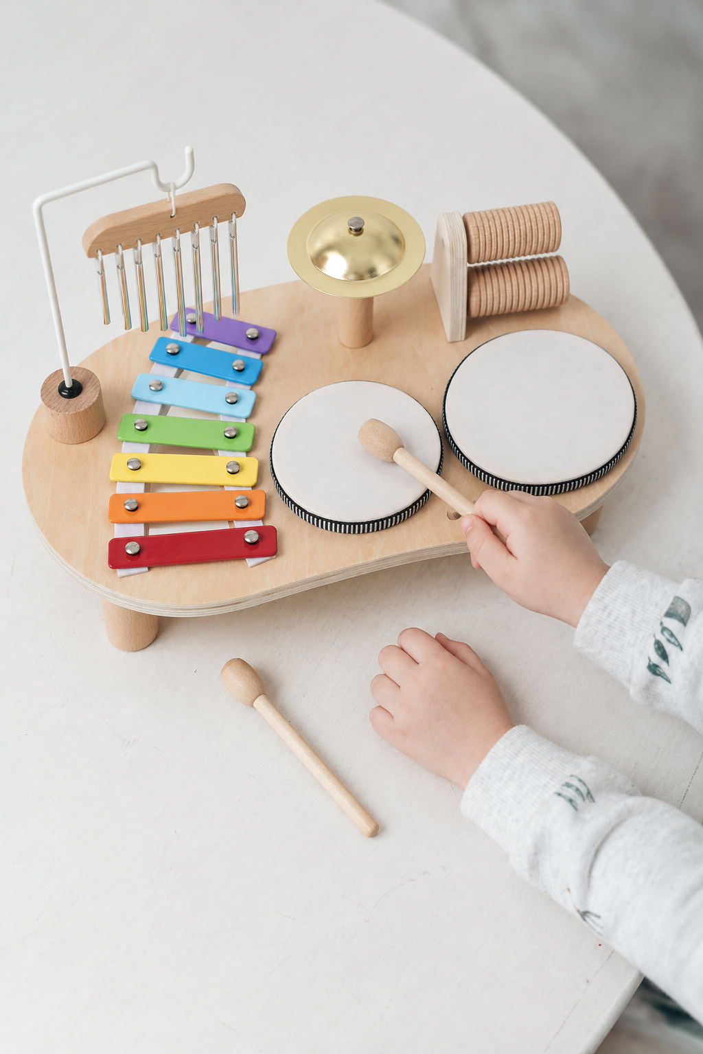 Child tapping a removable drum on the wooden music table