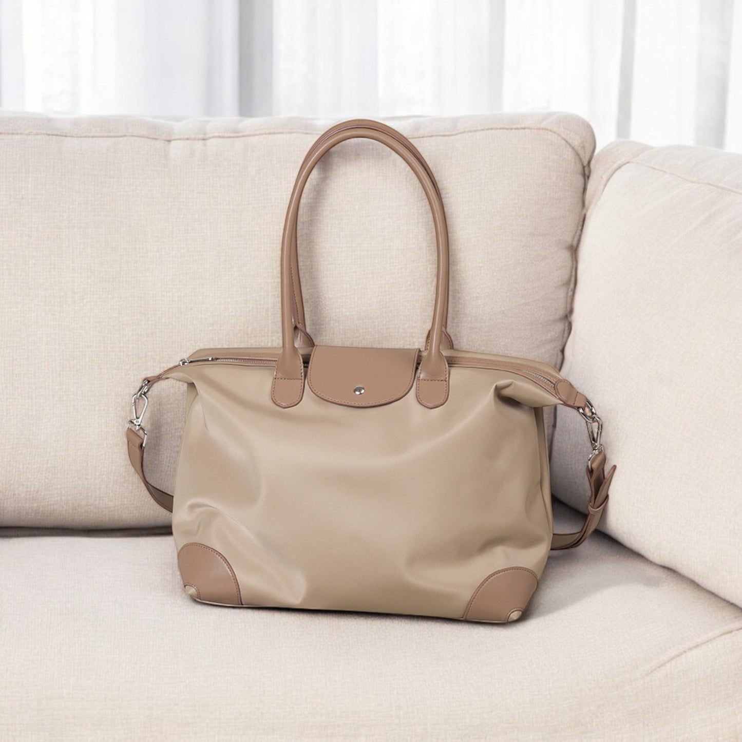 Beige handbag on a beige sofa with a white curtain background