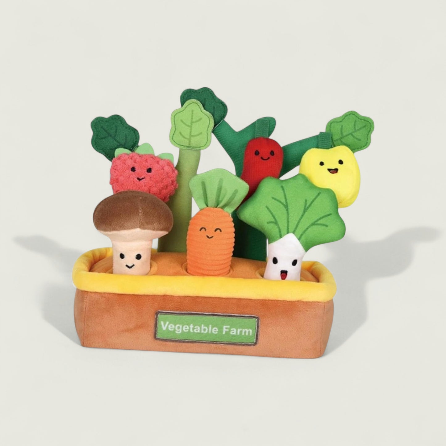 Toy vegetable set with smiling faces in a box labeled 'Vegetable Farm' on a light gray background