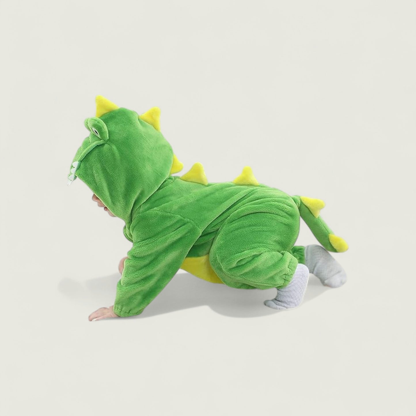 Child wearing a green dinosaur onesie on a light beige background