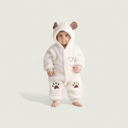 Baby wearing a white fluffy onesie with bear ears and paw prints on a light gray background