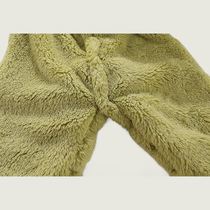 Close-up of a green fluffy blanket with a knot on a light gray background