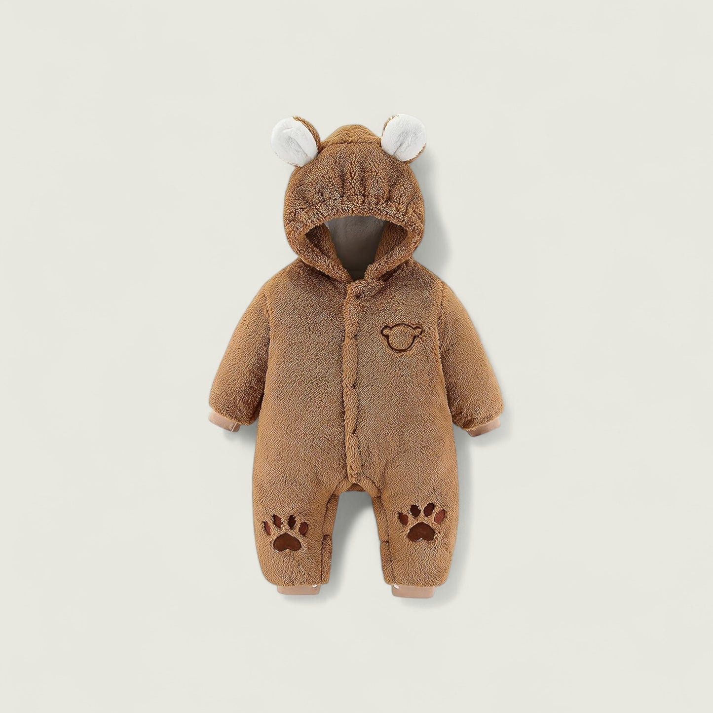 Brown baby onesie with bear ears and paw prints on a beige background