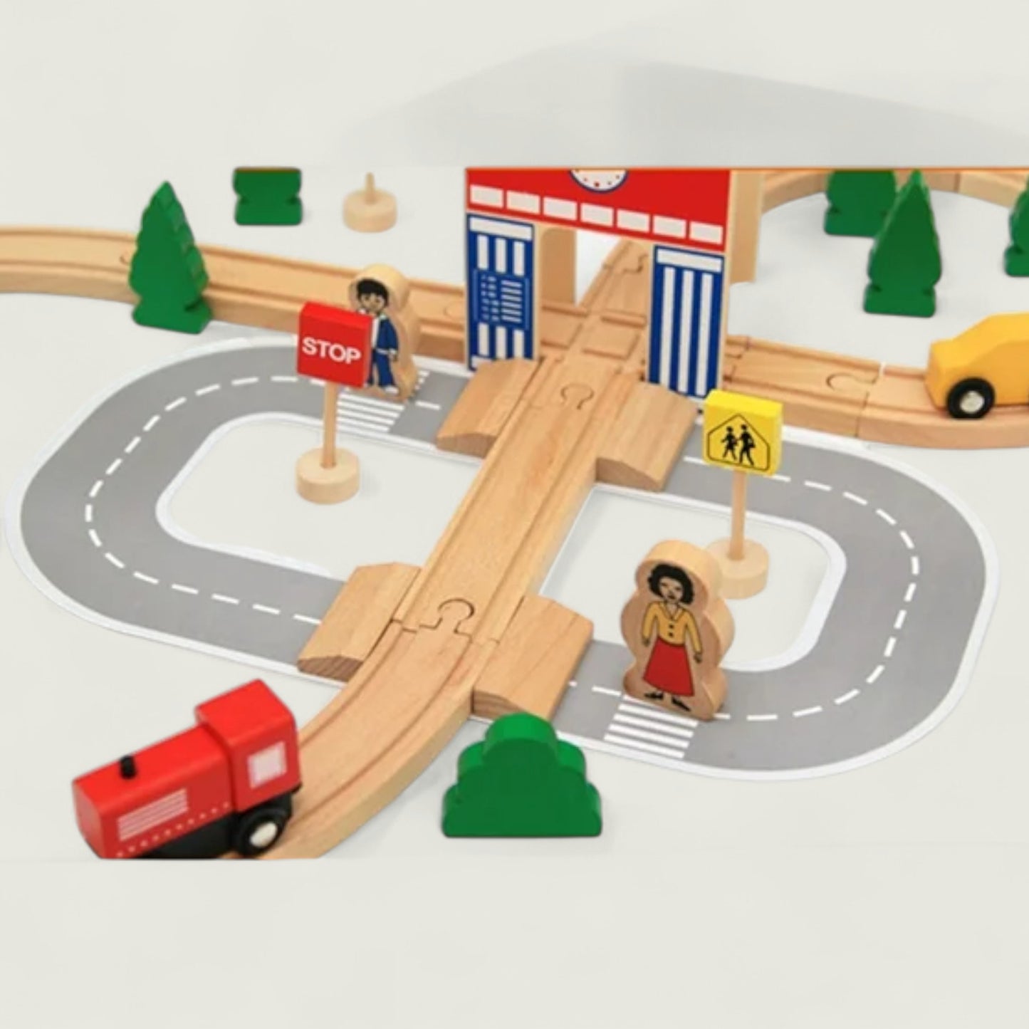 Wooden toy train set with tracks, road, and traffic elements on a white background