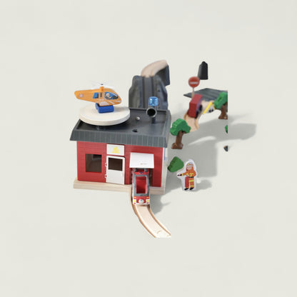 Toy fire station set with a red building, helicopter, and figures on a light gray background
