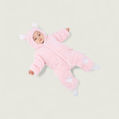 Baby in a pink snowsuit with bear ears on a light gray background