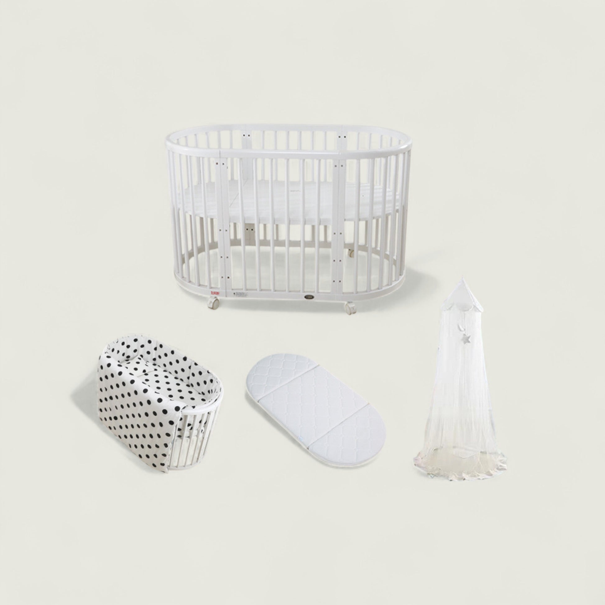 White crib with bassinet, mattress, and canopy on a light beige background