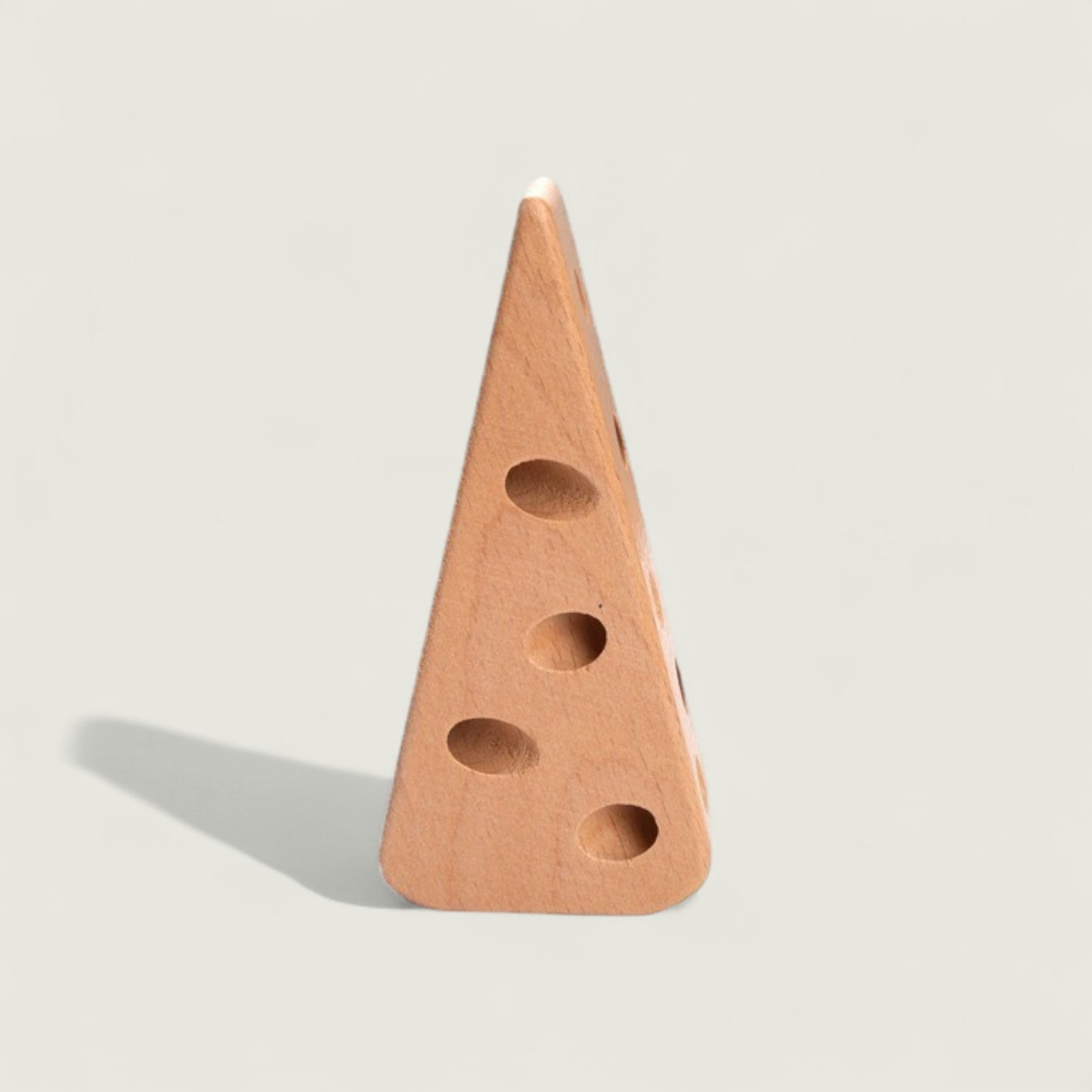Wooden cheese wedge with holes on a light gray background