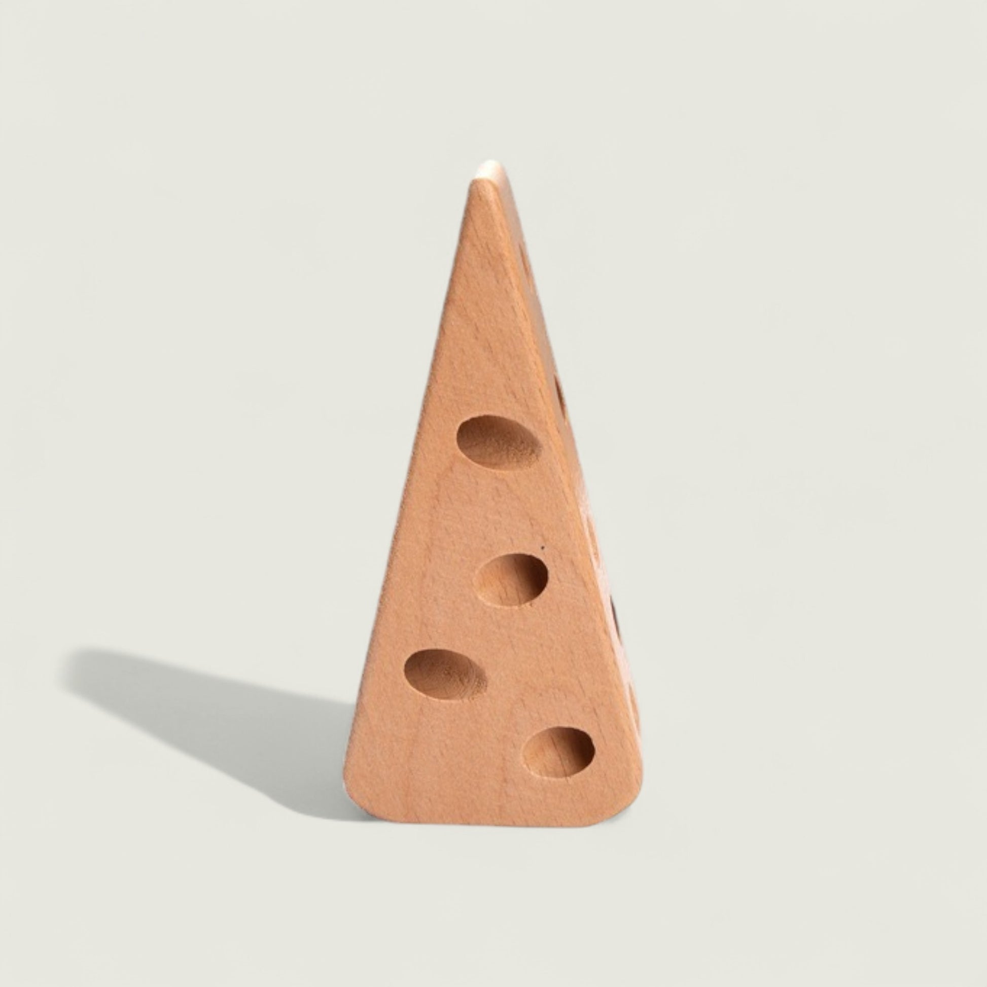 Wooden cheese wedge with holes on a light gray background