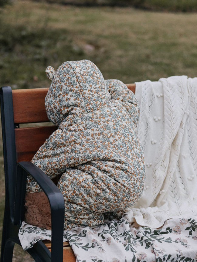 Person wrapped in a floral blanket sitting on a bench outdoors