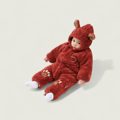 Baby in a red bear-themed onesie on a light beige background