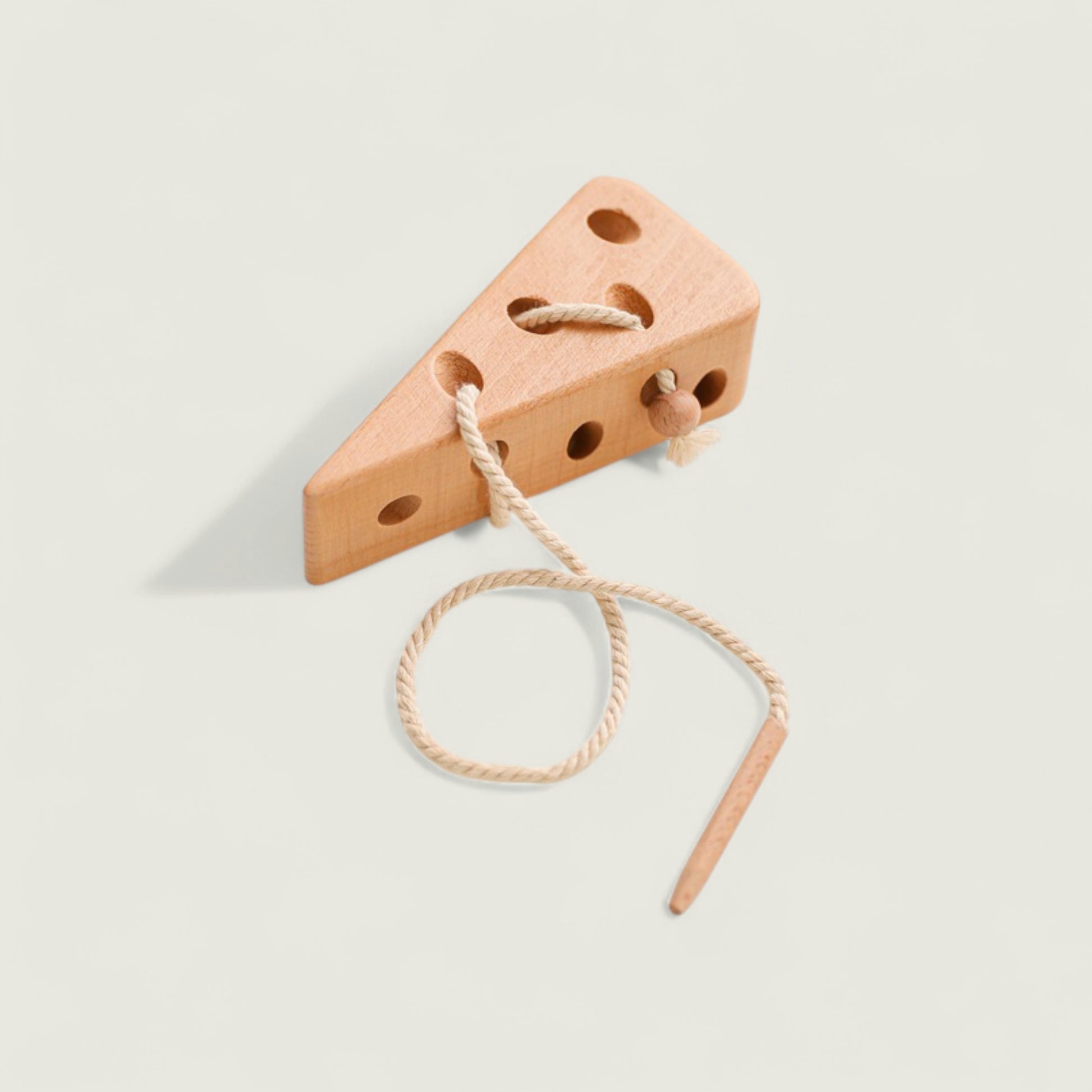 Wooden wedge-shaped toy with a string on a light gray background