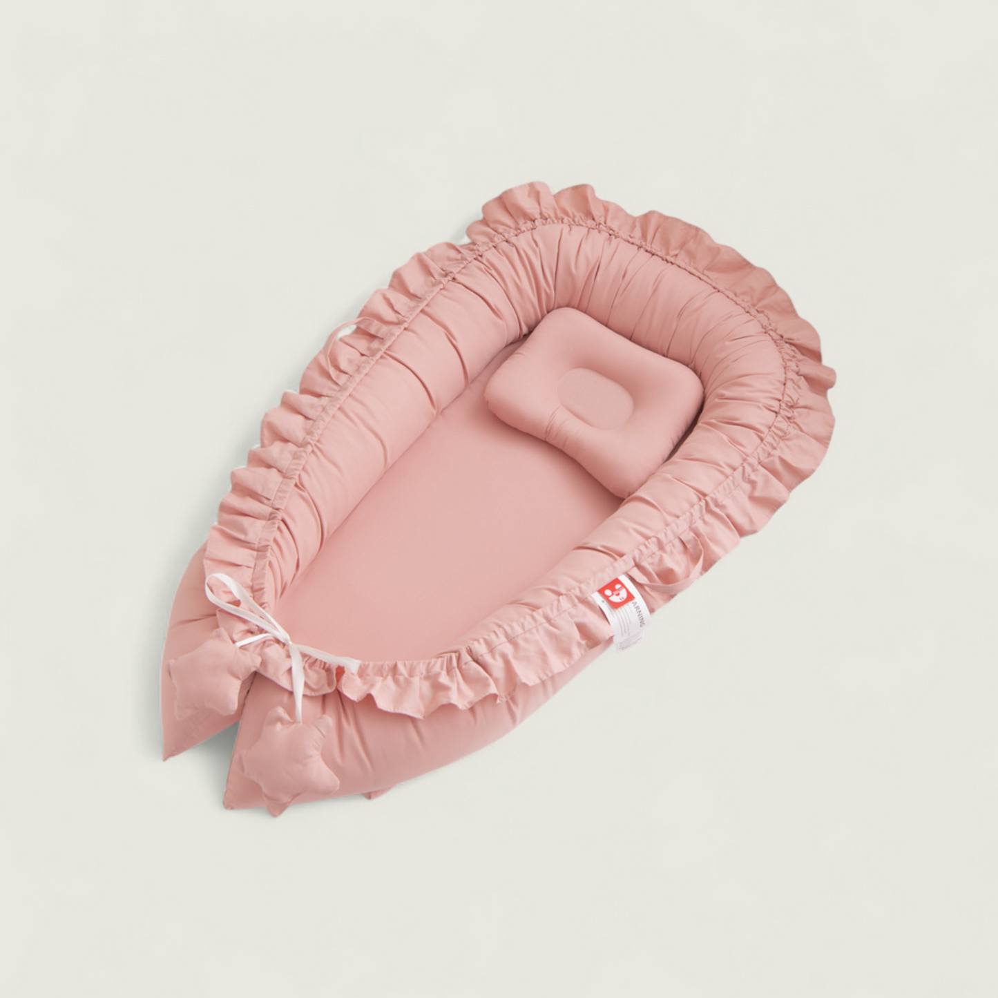 Pink baby crib with ruffled edges on a light beige background