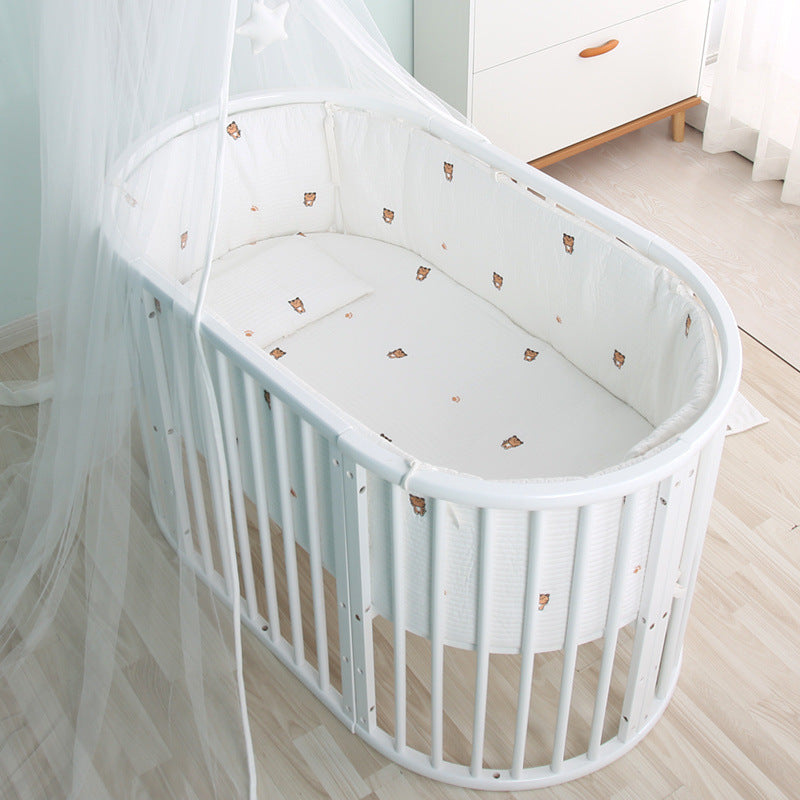 White crib with canopy in a room with light-colored wooden floor and white walls.