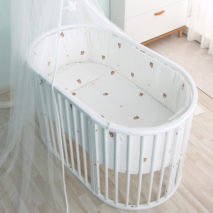 White crib with canopy in a room with light-colored wooden floor and white walls.
