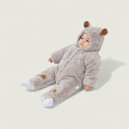 Baby in a gray bear onesie on a light beige background