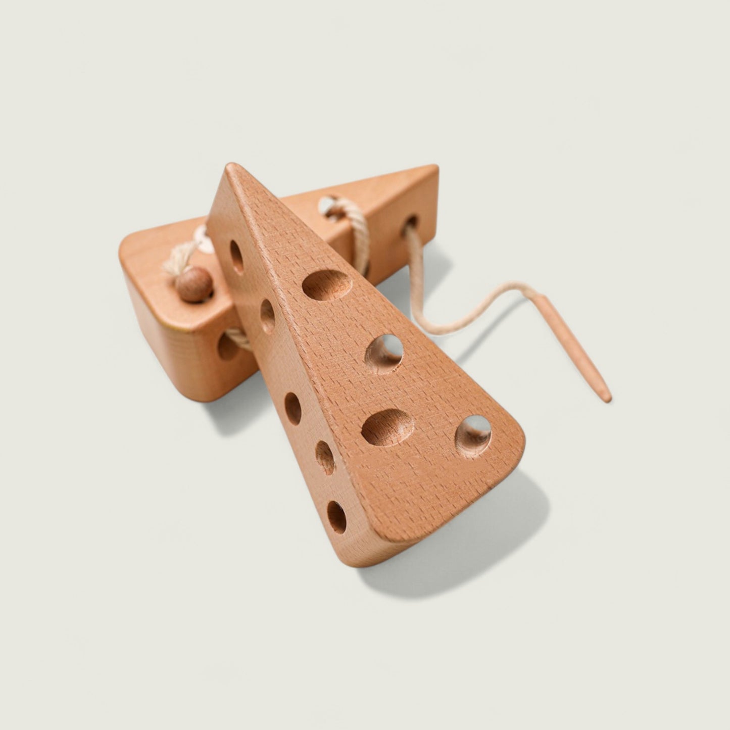 Wooden toy shaped like a cheese wedge with holes on a light background