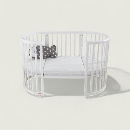 White crib with a gray cushion and star-patterned pillow on a light gray background