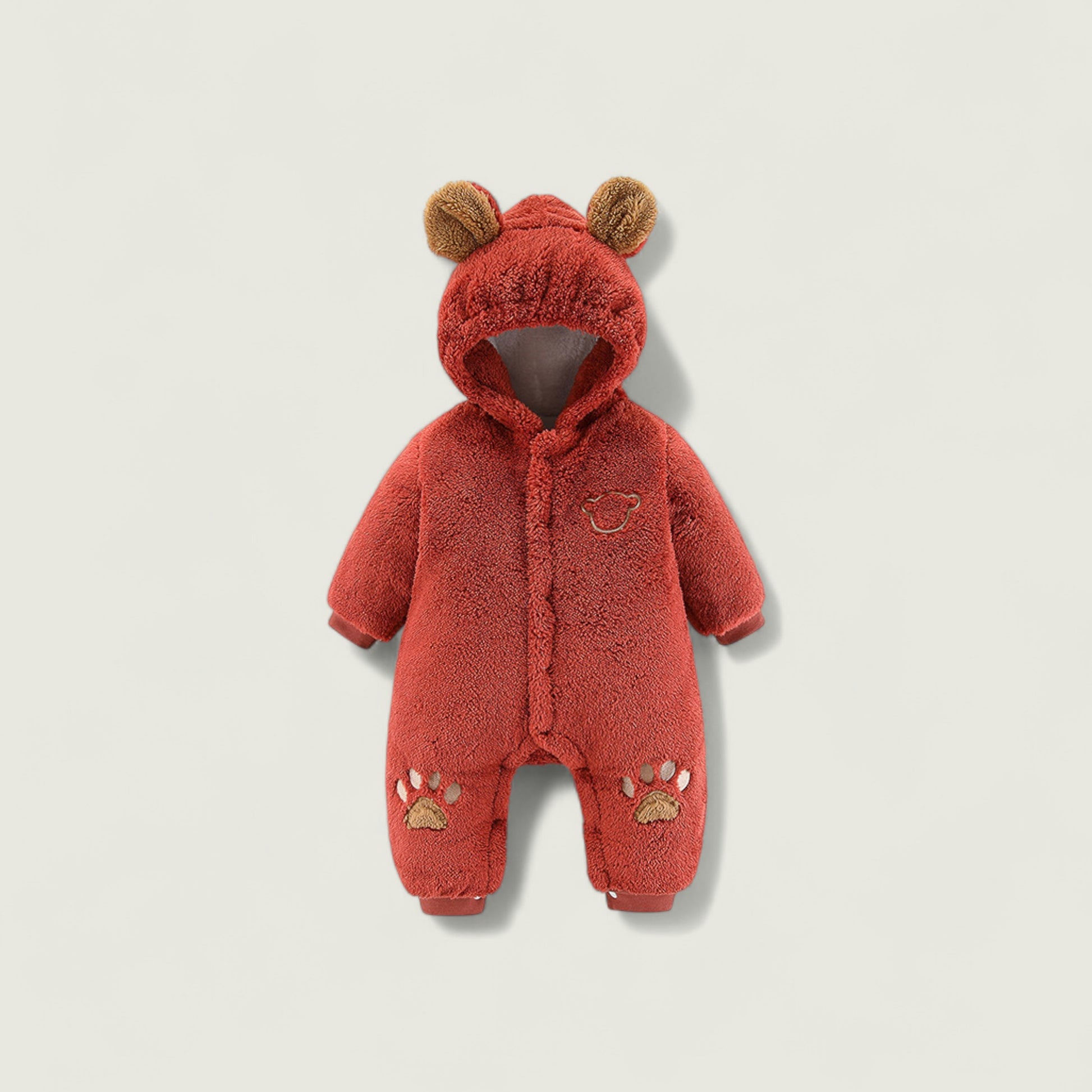 Red baby snowsuit with bear ears and paw prints on a beige background