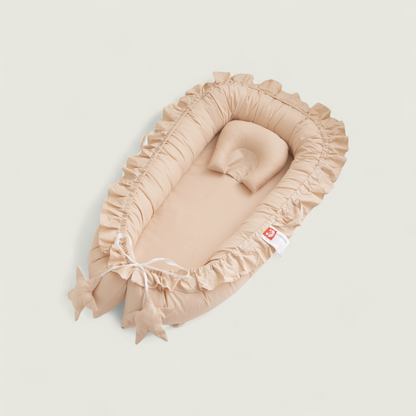 Beige baby crib with ruffled edges on a light gray background