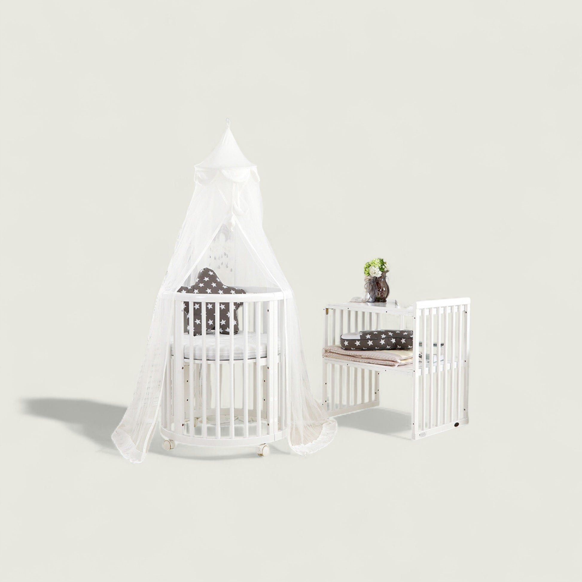White crib with canopy and matching changing table against a light gray background