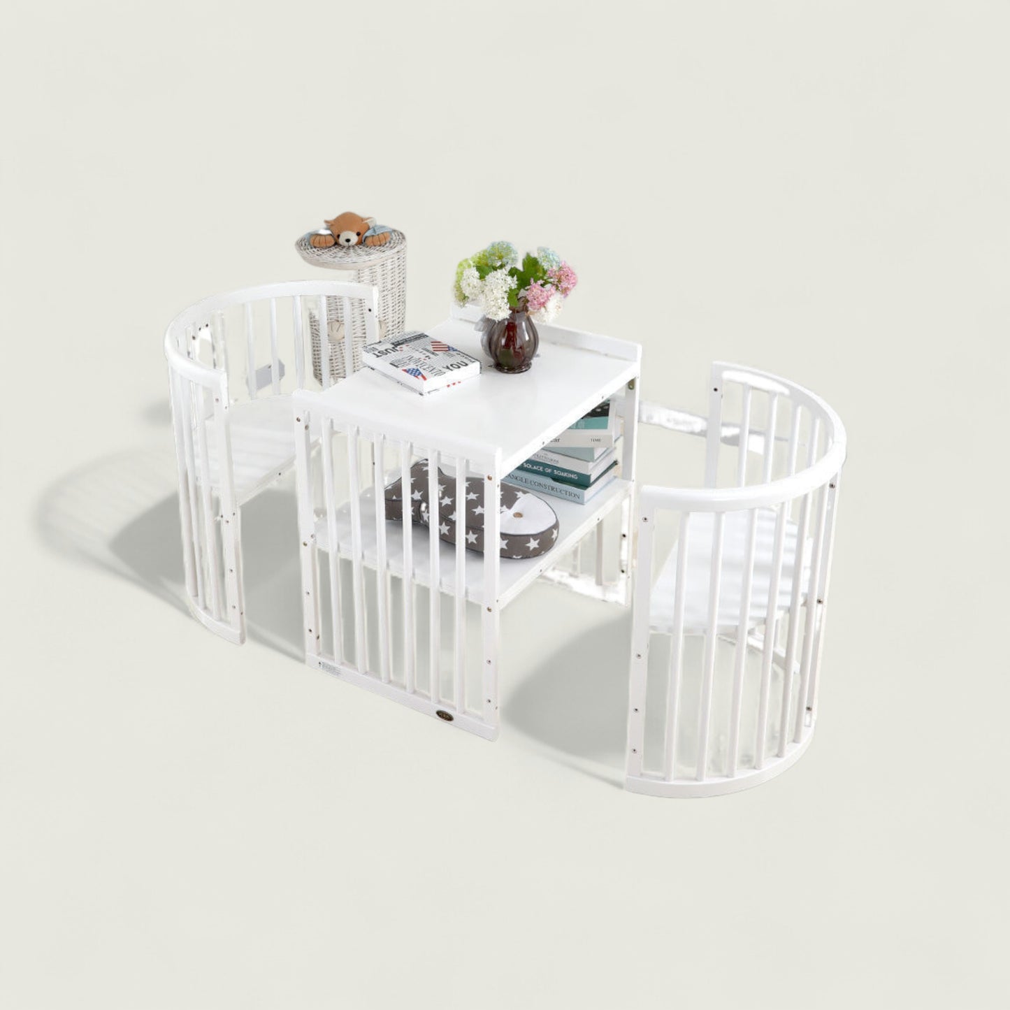 White crib with a small table and decorative items on a light gray background