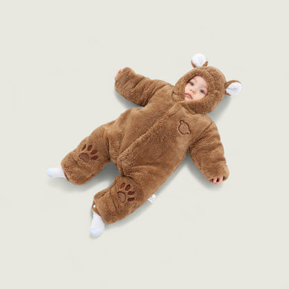 Baby in a brown bear onesie lying on a beige background