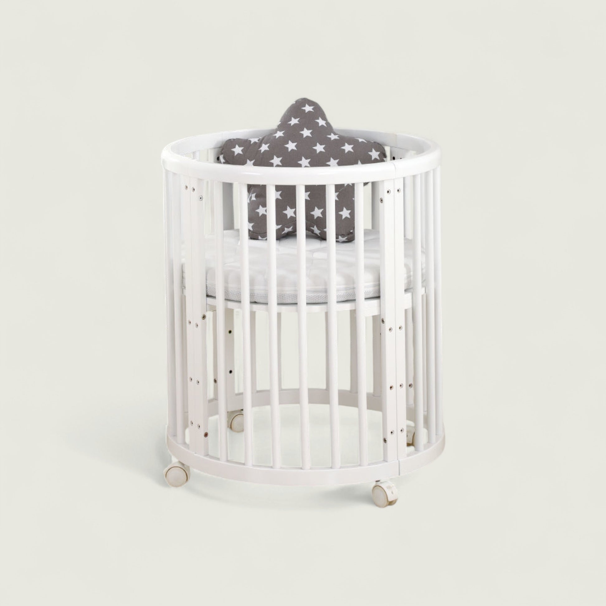White crib with a gray cushion with star patterns on a light gray background