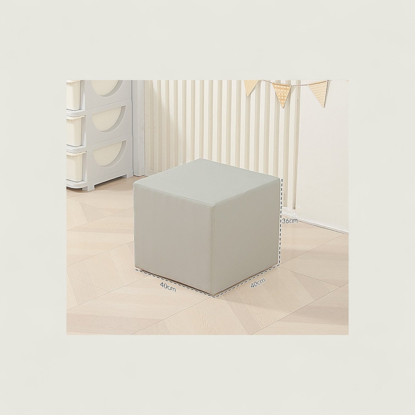 Gray cube ottoman in a minimalistic room with white walls and light-colored floor.
