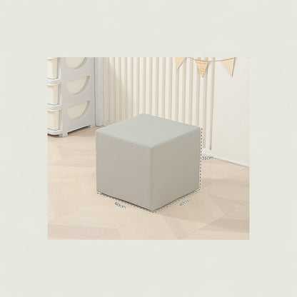 Gray cube ottoman in a minimalistic room with white walls and light-colored floor.