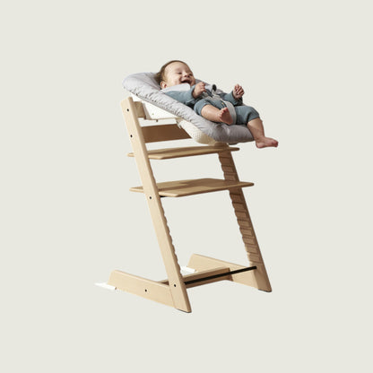 Wooden high chair with a baby sitting on a cushion against a light background. Pinterest chair