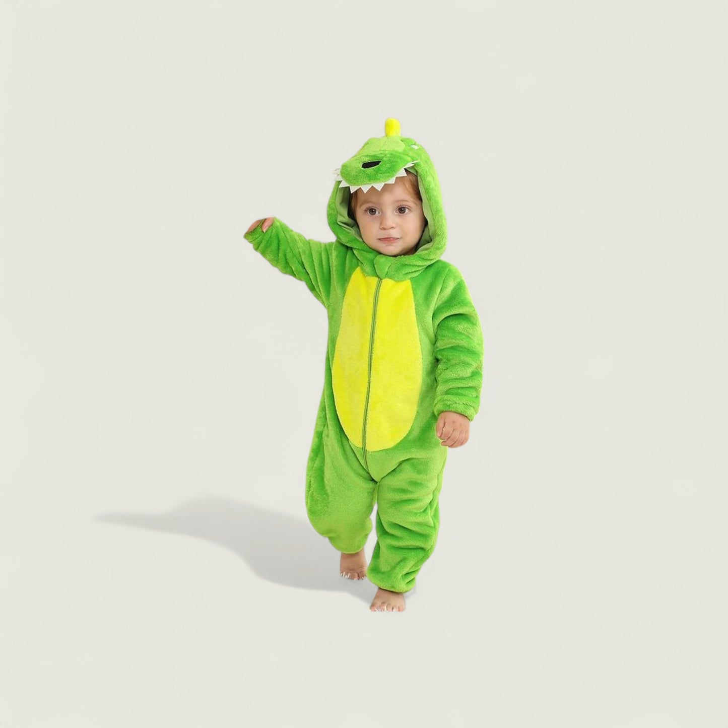 Child wearing a green dinosaur onesie on a light gray background