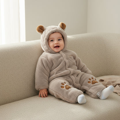 Baby in a bear-themed onesie sitting on a couch.