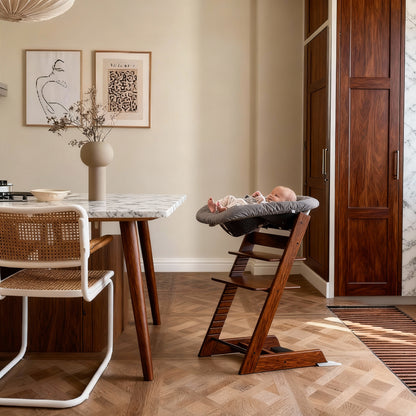 Wooden high chair in a room with a marble table and framed artwork on the wall.