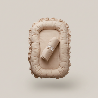 Beige baby nest with rolled blanket on a beige background