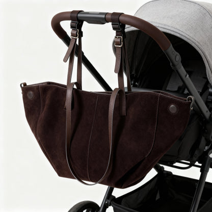 Brown leather baby carrier attached to a stroller on a white background