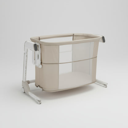 Beige baby crib with mesh side on a white background