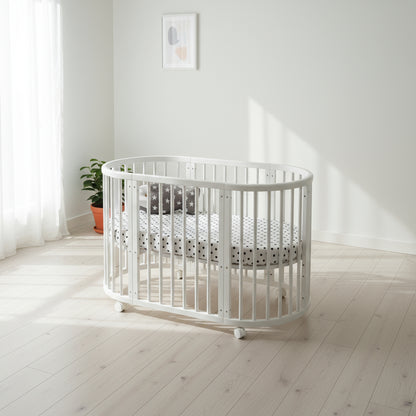 White crib in a bright, minimalistic room with light wood flooring and white walls.