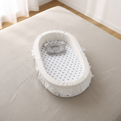 Baby bassinet with star-patterned mattress on a bed