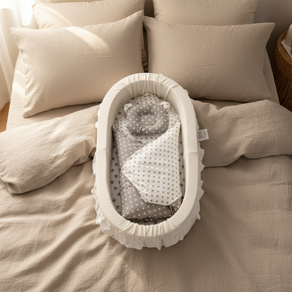 Baby bassinet with gray and white bedding on a beige bed
