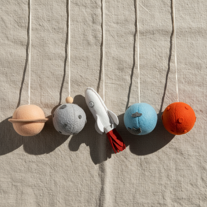 Toy space-themed mobile with planets and a rocket on a textured beige background