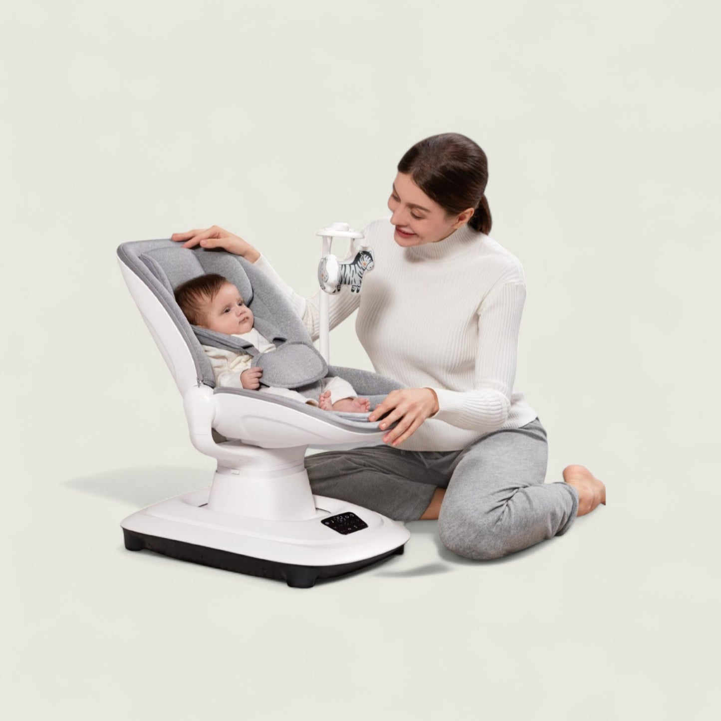 Woman sitting with a baby in a modern baby seat on a plain background